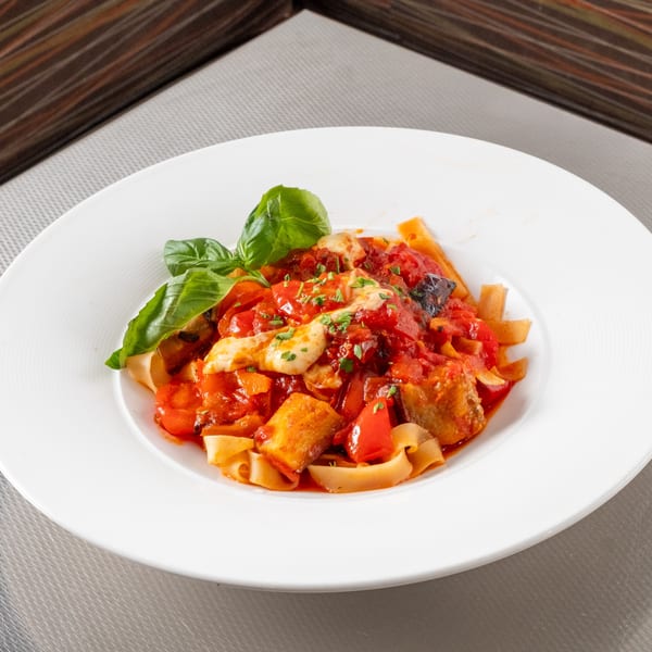 Wide pasta with chunky tomato sauce, eggplant, bell peppers, mozzarella, and fresh basil.