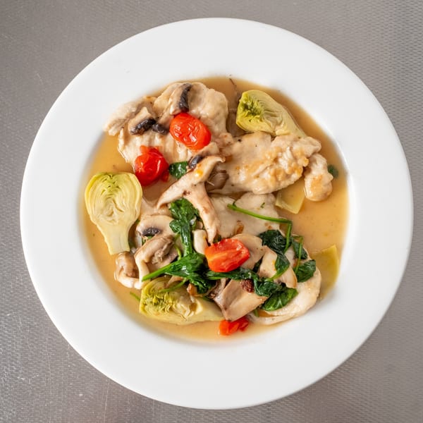 Chicken with mushrooms, spinach, cherry tomatoes, and artichoke hearts in a light sauce.
